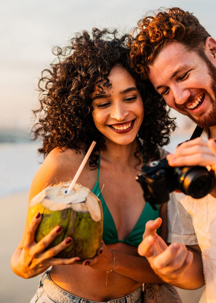 Young couple talking and looking photos on camera on the beach